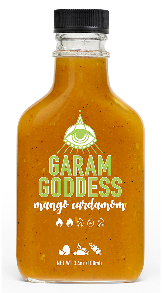 Garam Goddess Mango Cardamom hot sauce bottle with golden-yellow label, emphasizing its clean, vegan, and gluten-free profile and ingredients like ghost pepper, cardamom and cinnamon